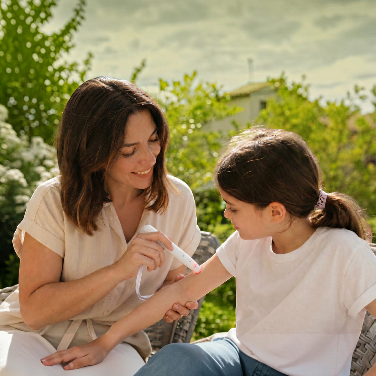 Une mère utilise le stylo anti-démangeaison Pik sur le bras de sa fille dans un jardin ensoleillé.